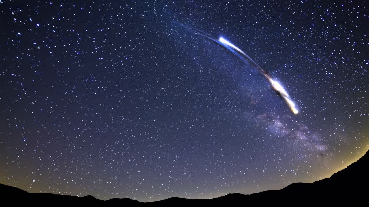 A wide-angle video captures a starry night sky over silhouetted mountains, showcasing a serene