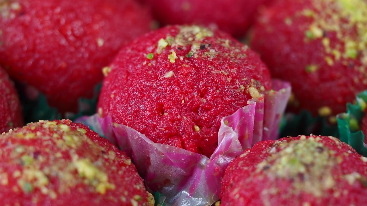 Dolci indiani rosso brillante guarniti con granella di pistacchi
