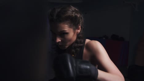 young woman in boxing gloves training with a punching bag in a boxing club