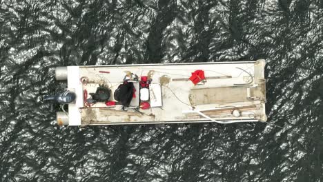 overhead shot of fishers on white fishing boat anchored in calm water