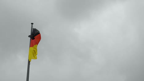 waving german flag with a dark cloudy sky background - slow motion shot