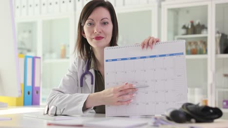 a female doctor pointing at a calendar in her office