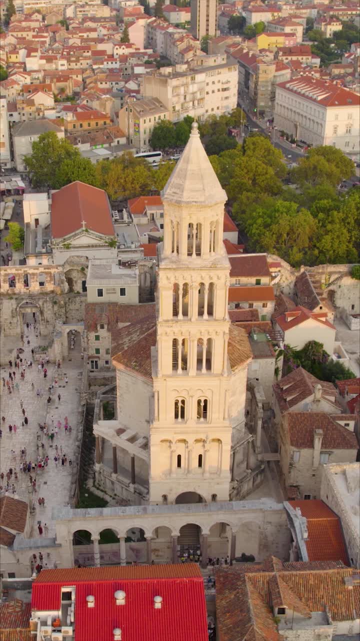 Vertical aerial focusing on the historic façade of Saint Domnius Cathedral in Split, Croatia, illuminated by soft golden hour light and showing its ornate architectural details