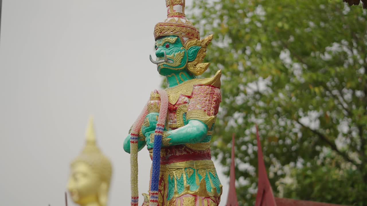 Golden Buddha Statue and Guardian Figure at a Temple in Thailand