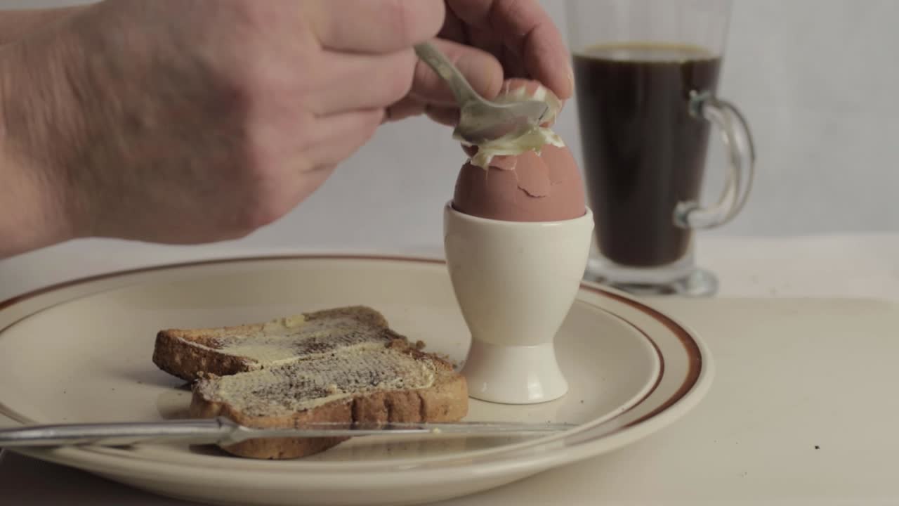 Hand eating boiled egg with toast medium shot