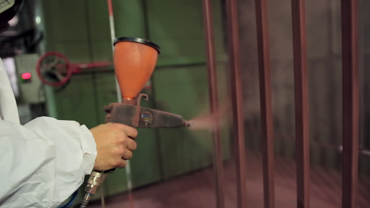 Hand painting steel. Hand of worker in protective work wear holding powder coating sprayer