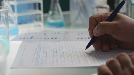hands of lab scientist filling out laboratory research documentation