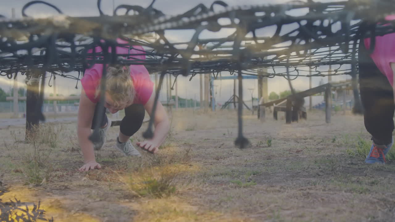Crawling under obstacle net, person participating in outdoor fitness challenge event