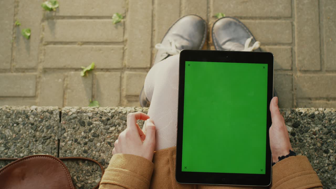 la chica está usando la tableta en el regazo al aire libre en un día soleado.