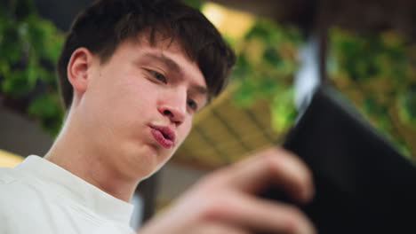 close head view very fair young lad smiling while playing game on phone screen capturing joyful expression light glint on face conveying playful youthful immersion in mobile entertainment moment
