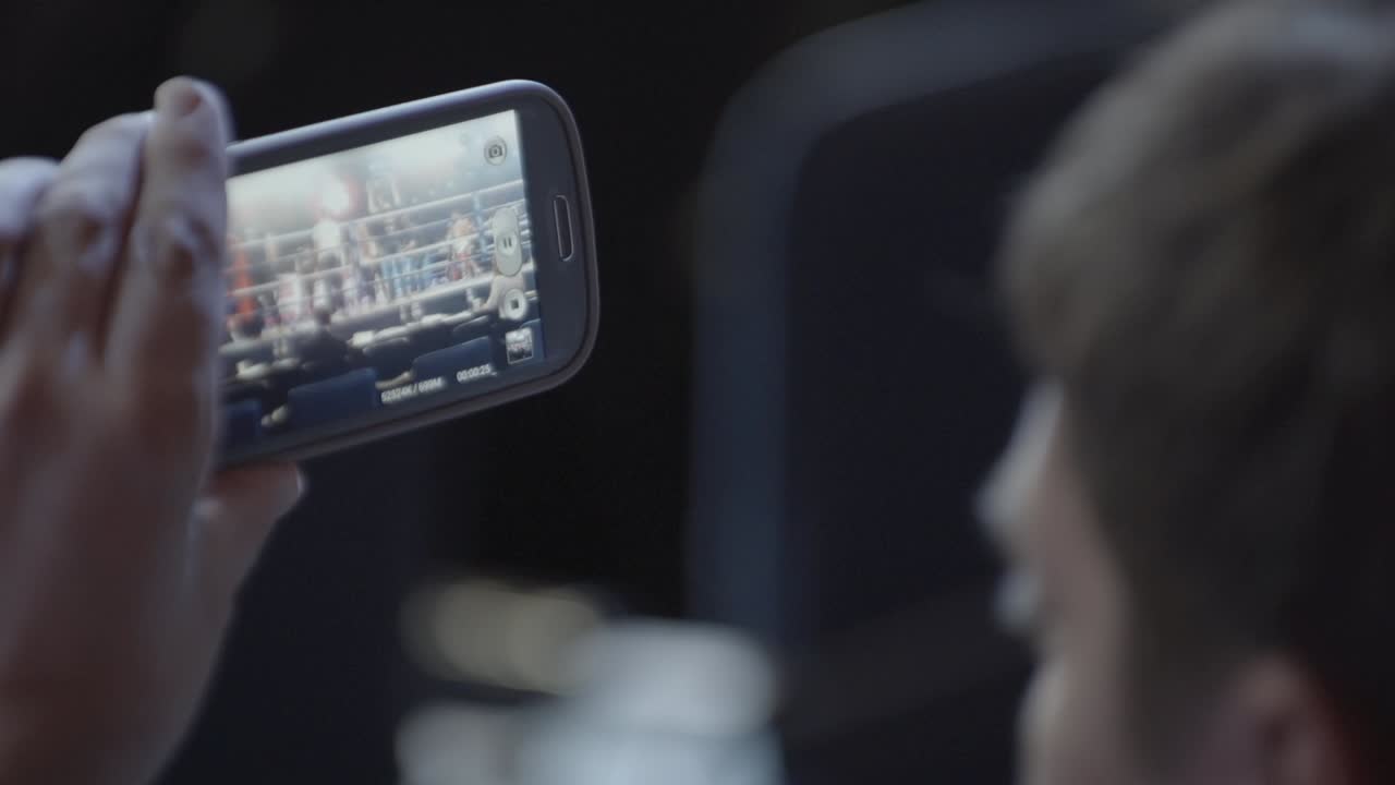 persona viendo un partido de boxeo en un teléfono inteligente