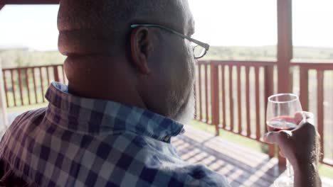senior african american man drinking wine on sunny terrace, slow motion