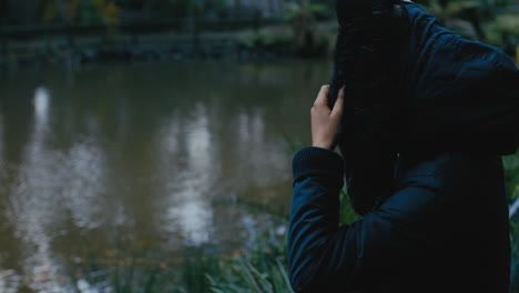 young woman sitting alone in park enjoying peaceful nature pond lonely teenage girl feeling depressed on cold cloudy day