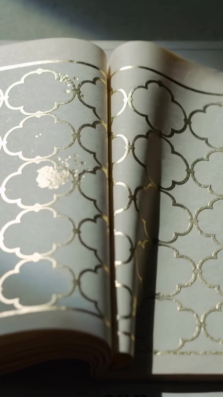 Vertical video: Moving cam through beam showing open book on desk for detail gold foil stain shadow