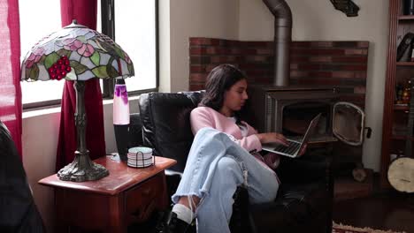 una joven juega en su computadora frente a una lámpara de lava y un horno antiguo