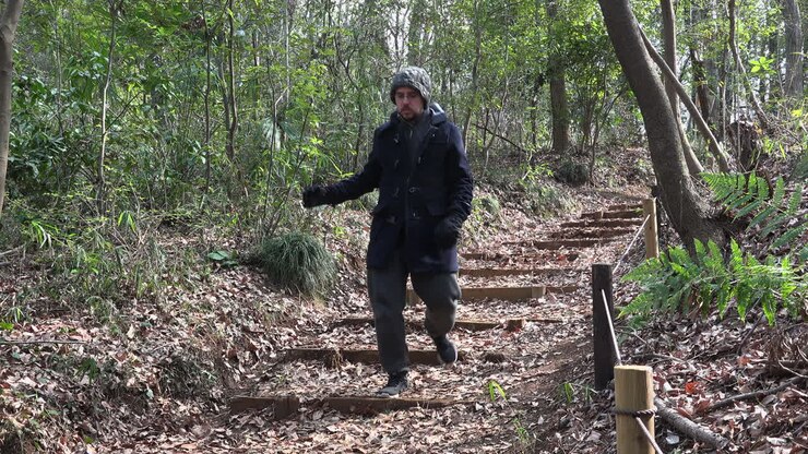 Un uomo caucasico sta scendendo la scalinata di un parco desolato di giorno