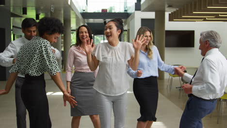 smiling multi-cultural business team having fun and dancing in office lobby