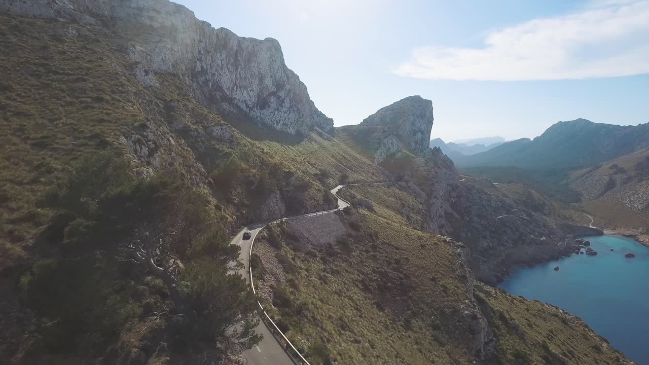 imágenes aéreas de 4k de un automóvil conduciendo por una carretera sinuosa junto a un acantilado en la enorme línea montañosa serra de tramuntana en mallorca, españa