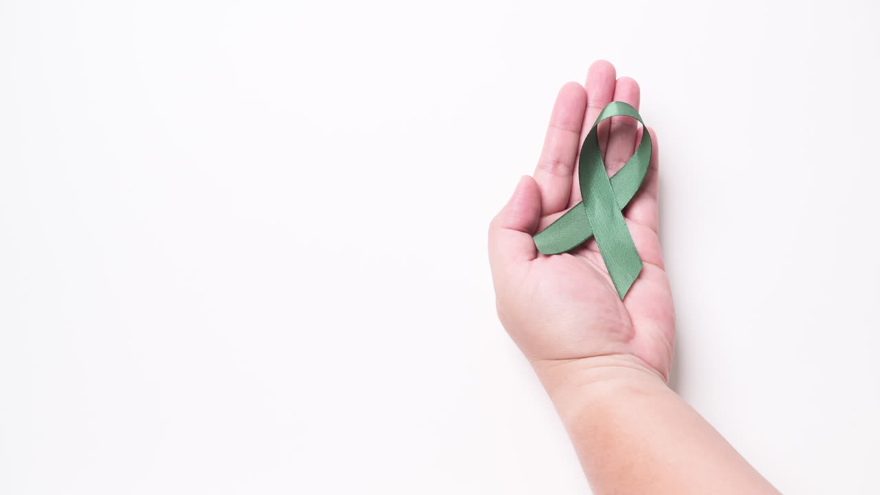 Dettaglio della mano maschile che posa un nastro verde su sfondo bianco