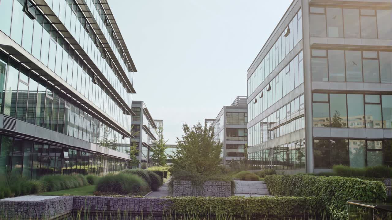 hermoso estanque artificial en el patio de la oficina, con muchas plantas verdes. la cámara se inclina hacia los edificios de oficinas de vidrio y el cielo despejado