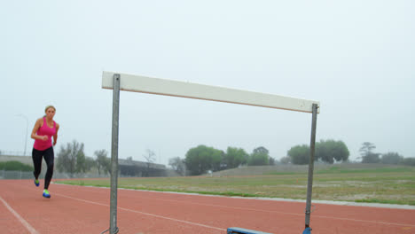 Ángulo-Bajo-De-Atleta-Caucásica-Saltando-Por-Encima-De-Un-Obstáculo-En-La-Pista-De-Carreras-4k