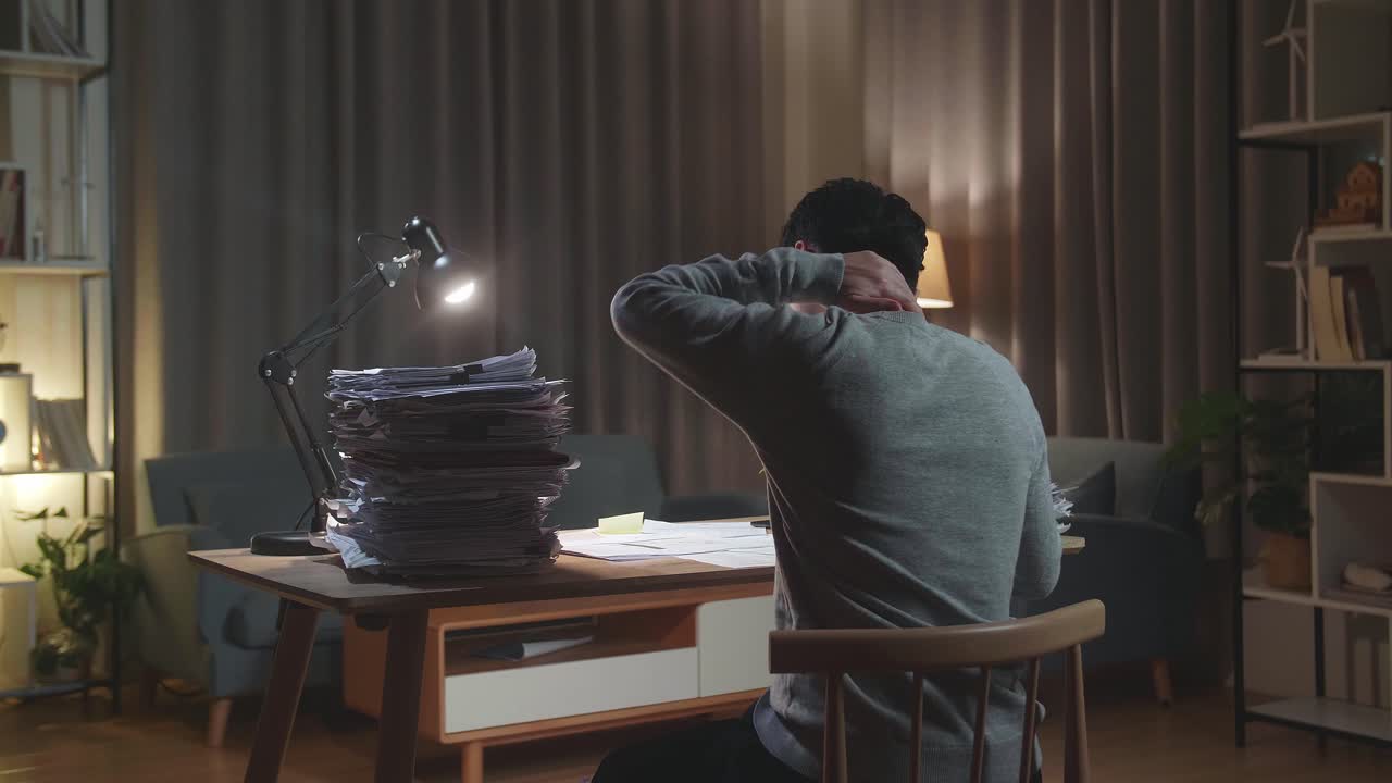 Back View Of Asian Man Having Neck Pain While Working Hard With Documents At Home