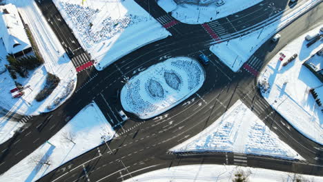 Cars-driving-over-a-giant-roundabout-equipped-with-traffic-lights-in-a-landscape-covered-with-white-snow-on-a-sunny-day