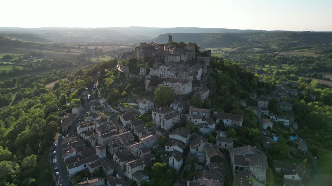 Drone aerial view in France countryside small old medieval brick town on a mountain top surrounded by green fields vertical descend on a sunny day in Cordes Sur Ciel