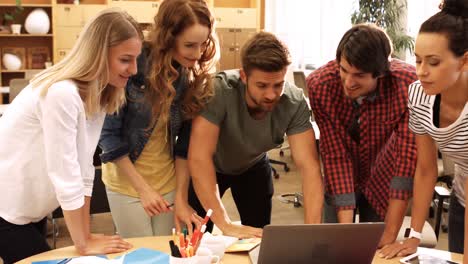 group of business executives discussing over laptop at their desk