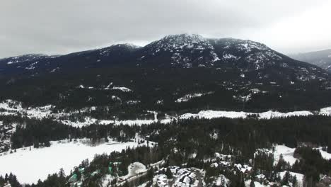 Drone-in-flight-over-winter-village-built-for-leisure-in-thick-of-rocky-mountains