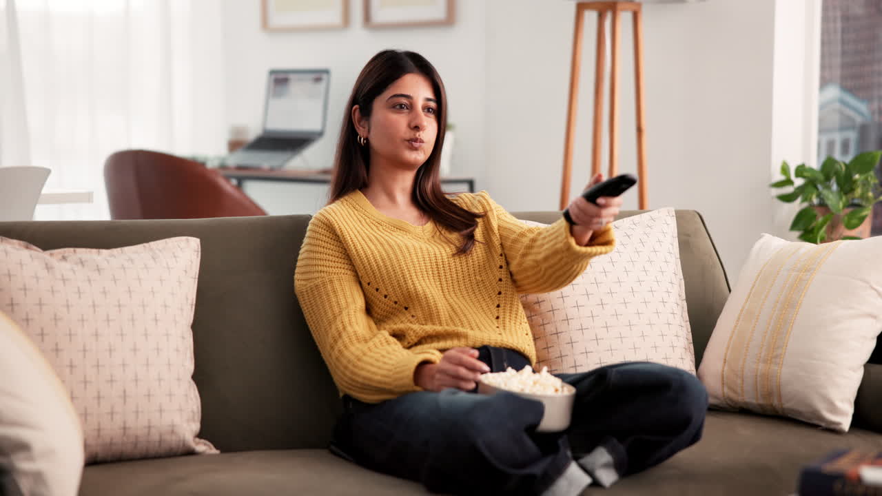 Donna che guarda la televisione seduta su un divano