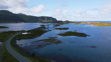 fredvang-brücke auf den lofoten im norden norwegens, umgeben vom meer mit ozeanwasserwellen, die an einem sonnigen, aber bewölkten tag im sommer in hellem türkisblau schimmern