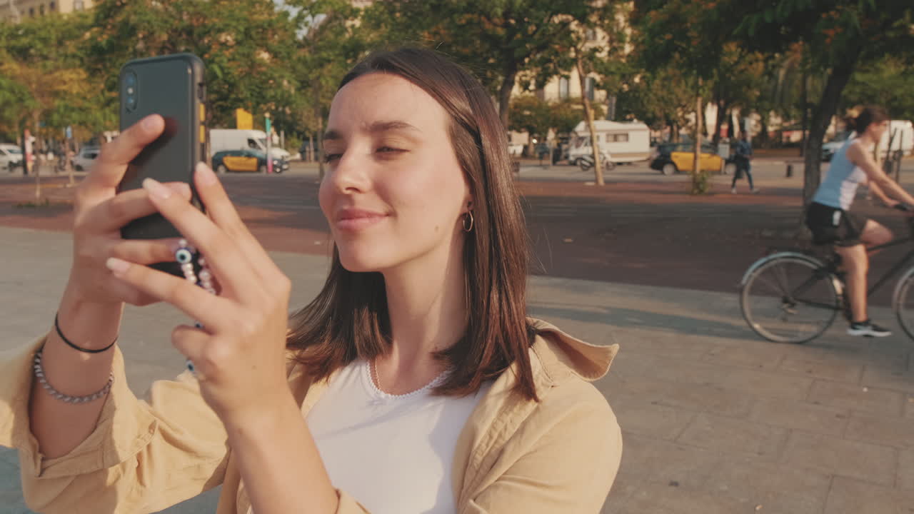 Jovem sorrindo enquanto usa smartphone ao ar livre