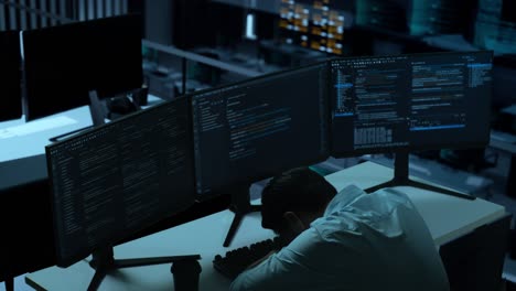 side view of tired asian man developer yawning before sleeping while write code with multiple computer screens in the office