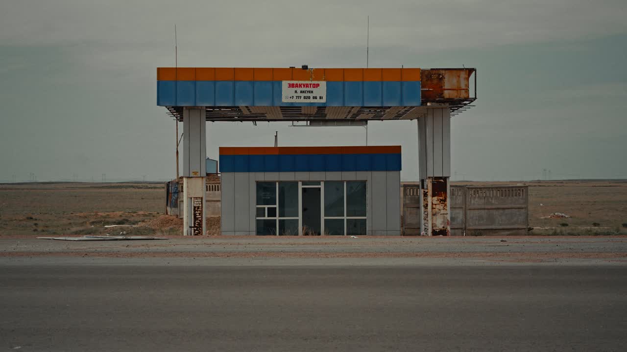 Un Tir passa accanto a una stazione di servizio abbandonata in un paesaggio desolato.