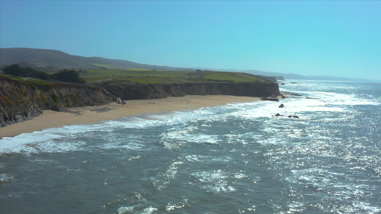 Stunning Aerial View of a Secluded Beach with Cliffs and Waves