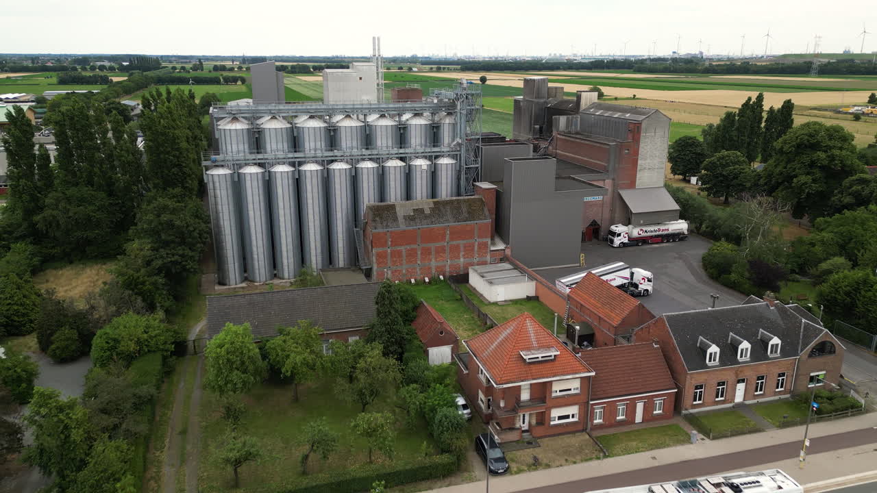 Modern grain silos and farm buildings near busy street, aerial view