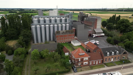 Modern-grain-silos-and-farm-buildings-near-busy-street,-aerial-view