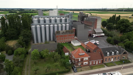 modern grain silos and farm buildings near busy street, aerial view