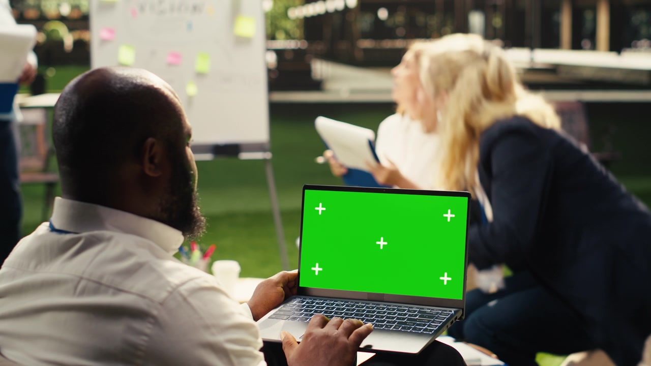 Professionista che lavora al laptop con schermo verde in una riunione d'ufficio