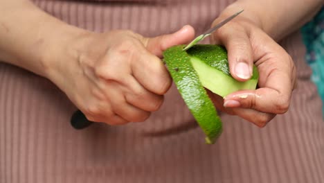 una mujer pelando un aguacate.