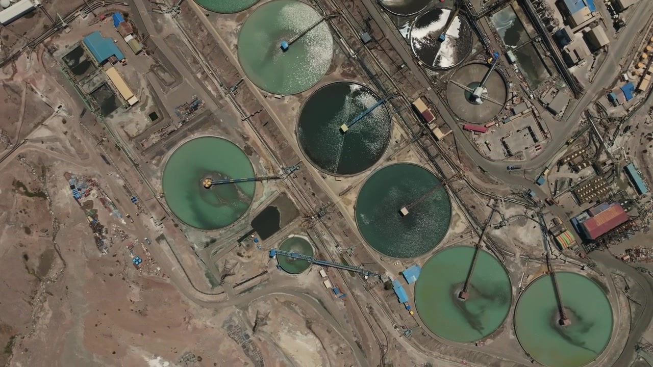 High-angle drone footage revealing large circular tanks used for tailings thickening and water recovery in a copper mining processing plant located in Chile.