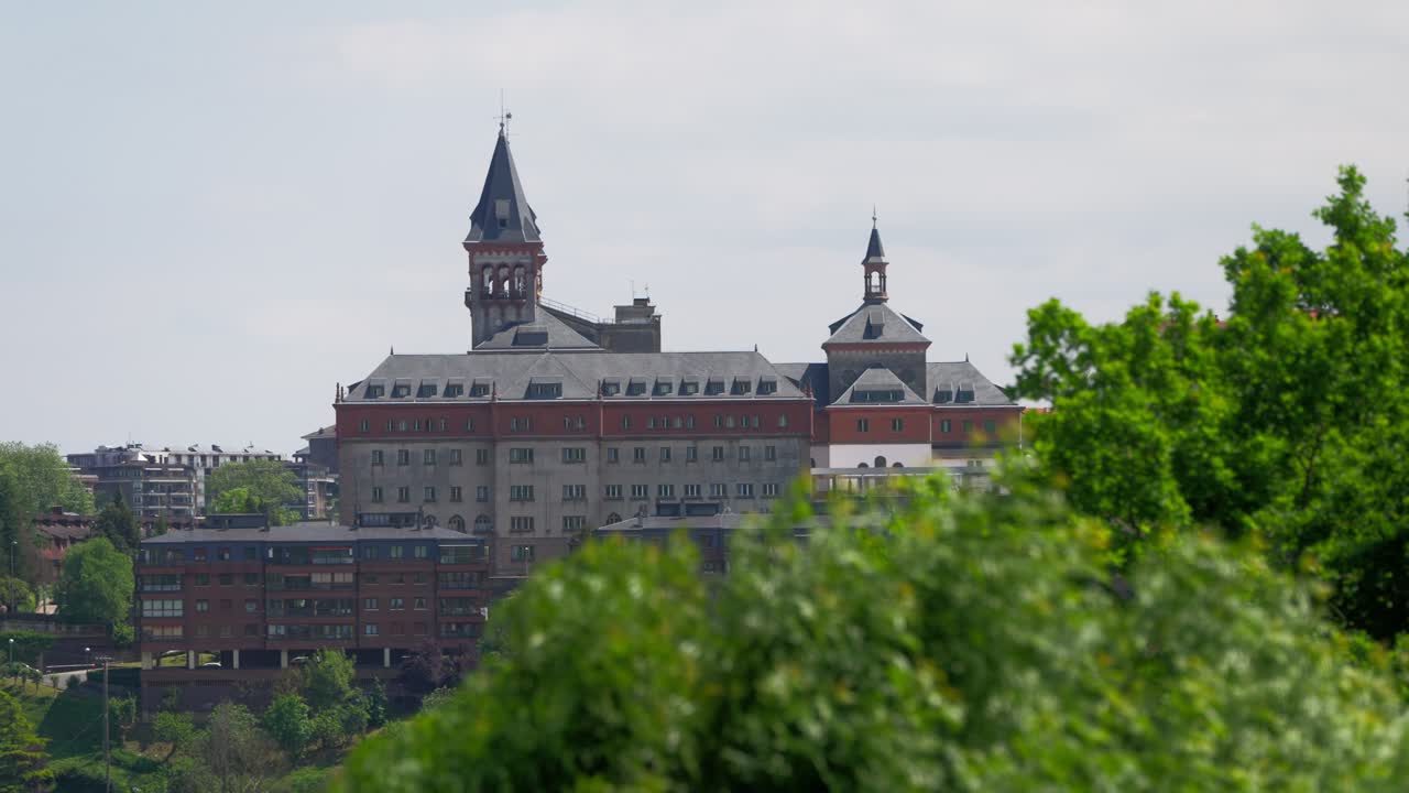 Focus pull from slow motion bushes to Historic palace-like building in San Sebastian