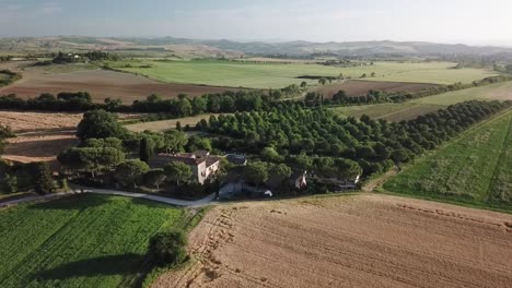 aerial view of rustic farmhouse and orchards in the rolling hills of tuscany, italy