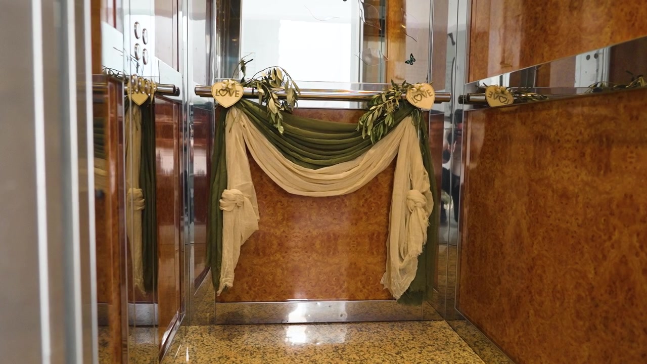 Una decoración especial en un ascensor presenta flores y cortinas para un evento de boda. El escenario es en una zona céntrica, mostrando amor y celebración para el día especial de una pareja