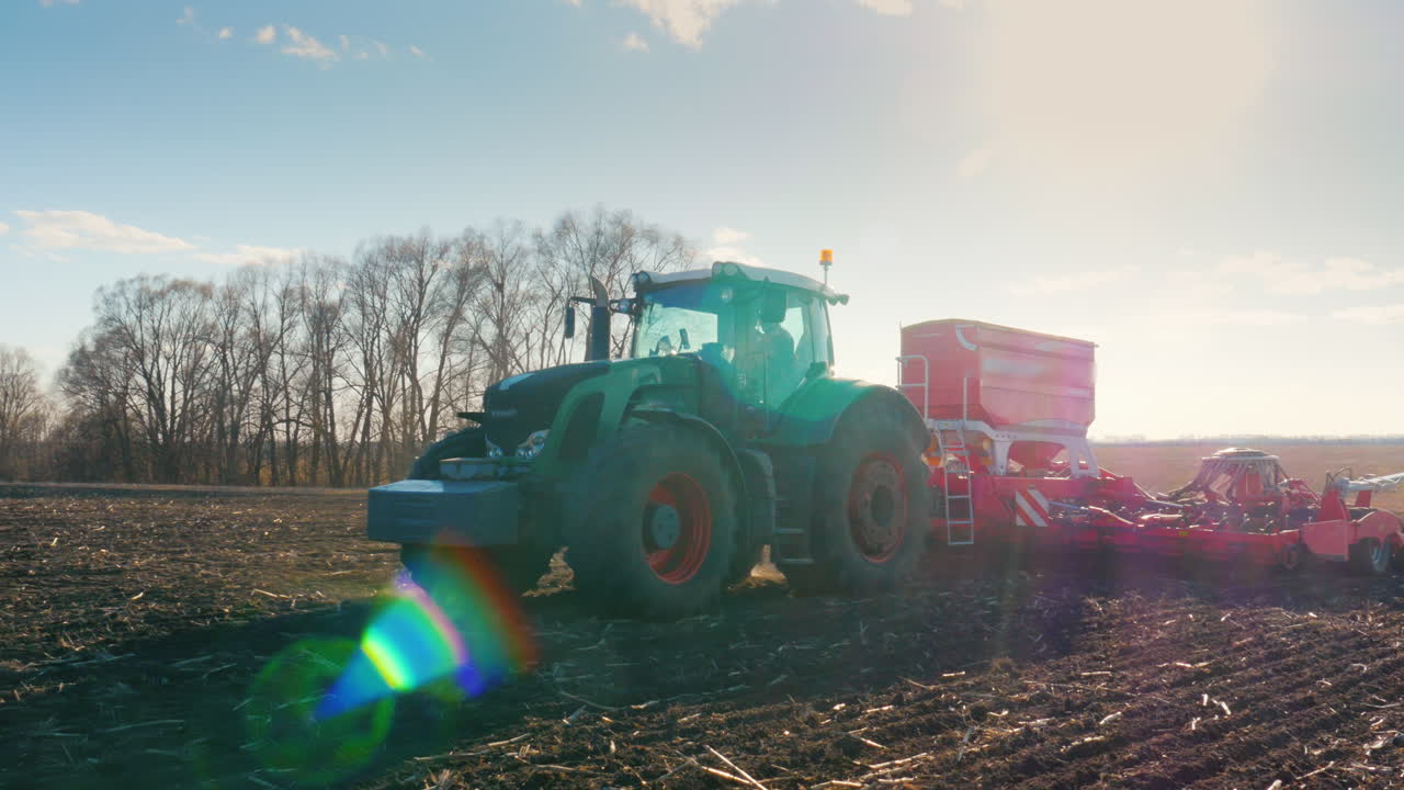 스테디캠 플라이 어라운드 샷:트랙터가 잡초 제거를 위한 필드 농업 메커니즘을 당깁니다.