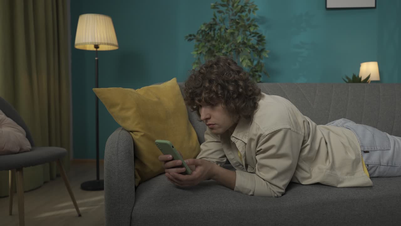 Young man relaxing on a couch using a smartphone
