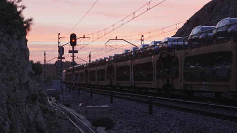 cargo-train-carrying-new-cars-passes-on-railroad-track-during-early-sunrise