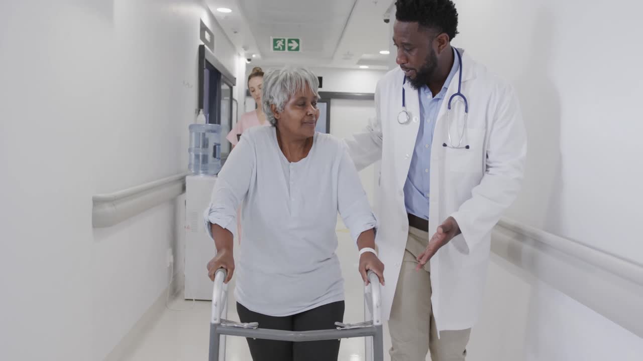 Glückliche, vielfältige Ärzte und Ärztinnen unterhalten sich mit einer älteren Patientin auf dem Flur, in Zeitlupe.