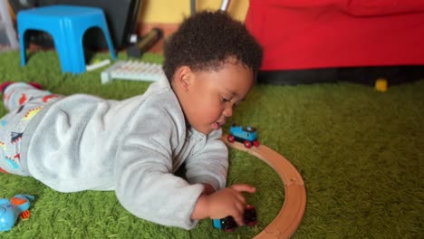 two year old exotic and cute afroeuropean child playing with his toy train at home
